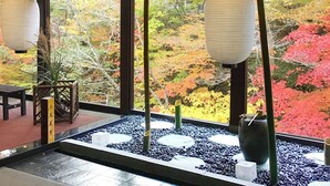 A traditional Japanese room with tatami flooring, a shoji screen, and a view of autumn foliage through large windows. - Livemax Resort Kawamata Onsen (Nikko)