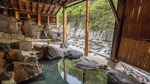 A traditional Japanese onsen with a clear hot spring, wooden beams, and a rocky landscape. - Livemax Resort Kawamata Onsen (Nikko)