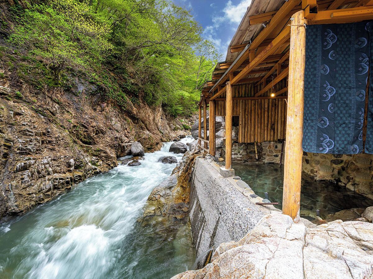 A wooden structure with a stone retaining wall beside a flowing river.