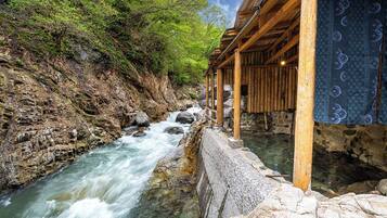 A wooden structure with a stone retaining wall beside a flowing river.