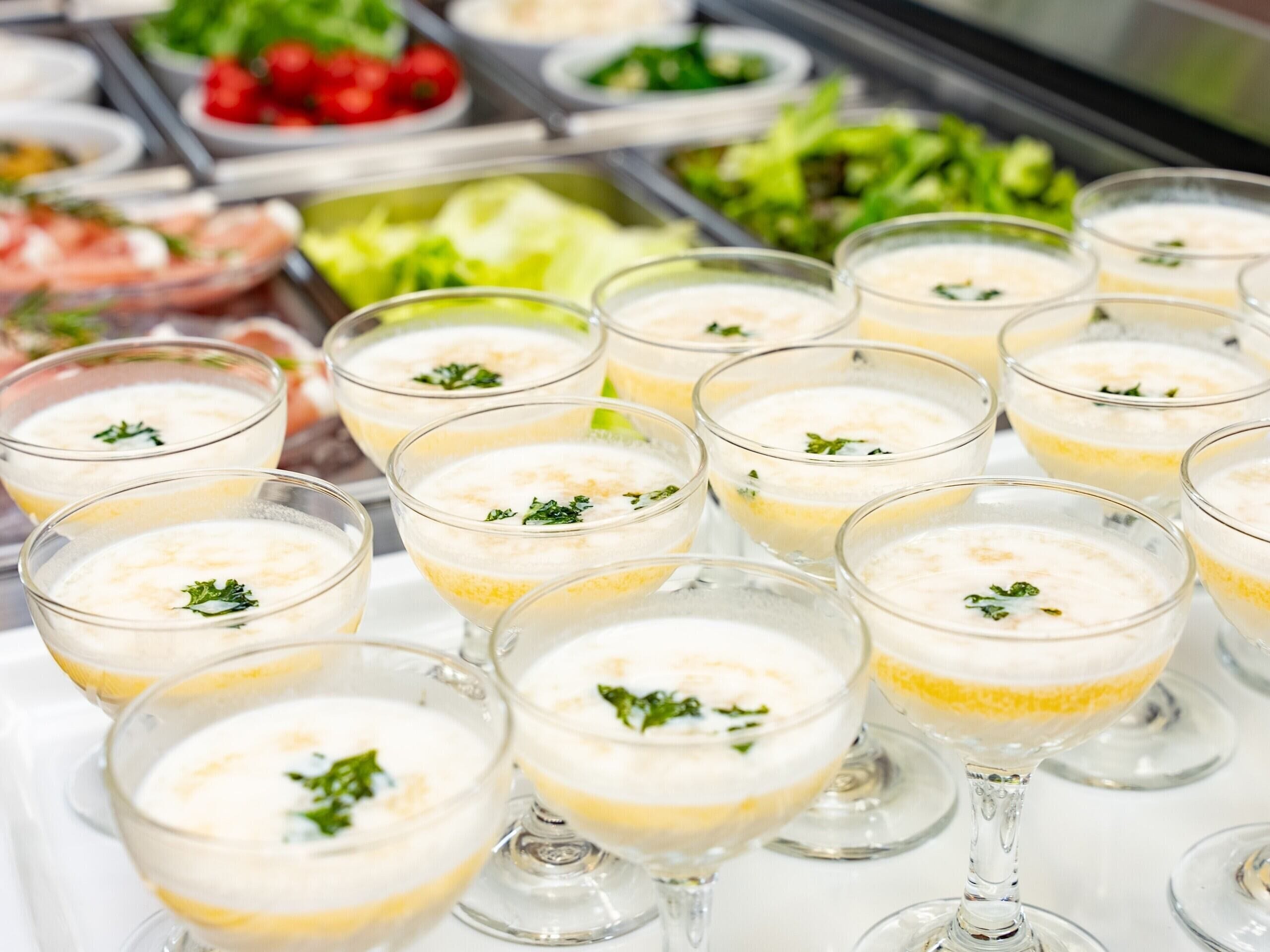 Un buffet proposant divers plats et boissons, notamment un dessert en couches servi dans des verres transparents.