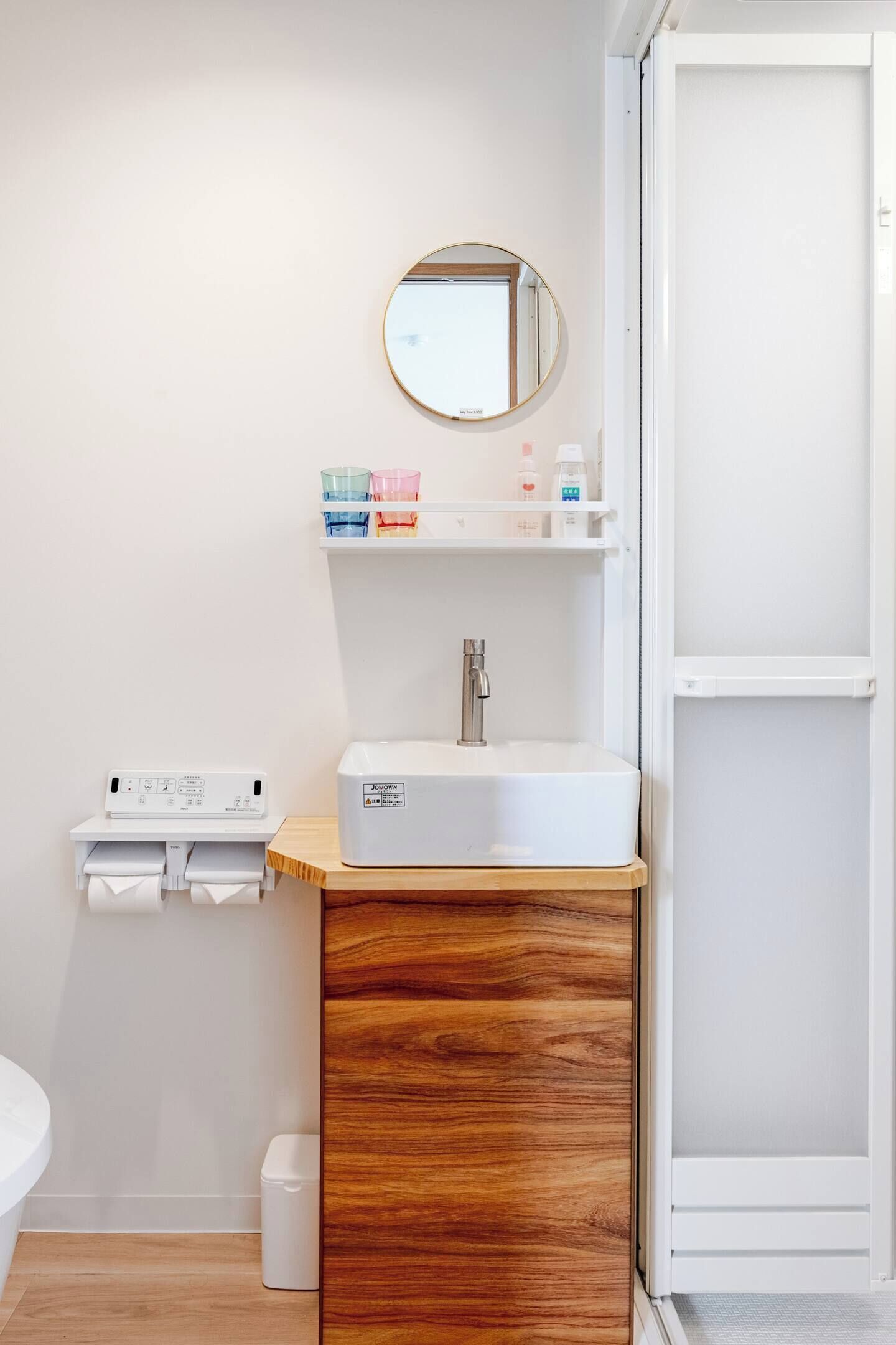 A bathroom with a white sink, mirror, and shelf with toiletries.