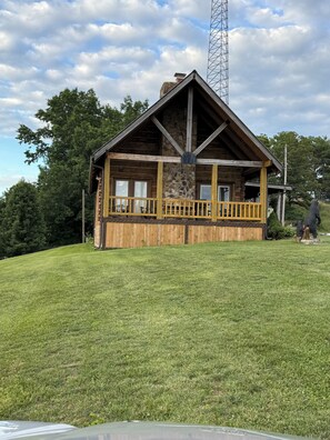 Eine Holzhütte mit Stein Fundament, einem Balkon und einem hohen Funkturm im Hintergrund.