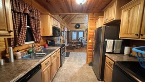 A kitchen with wooden cabinets, a granite countertop, a stainless steel refrigerator, and a dishwasher.