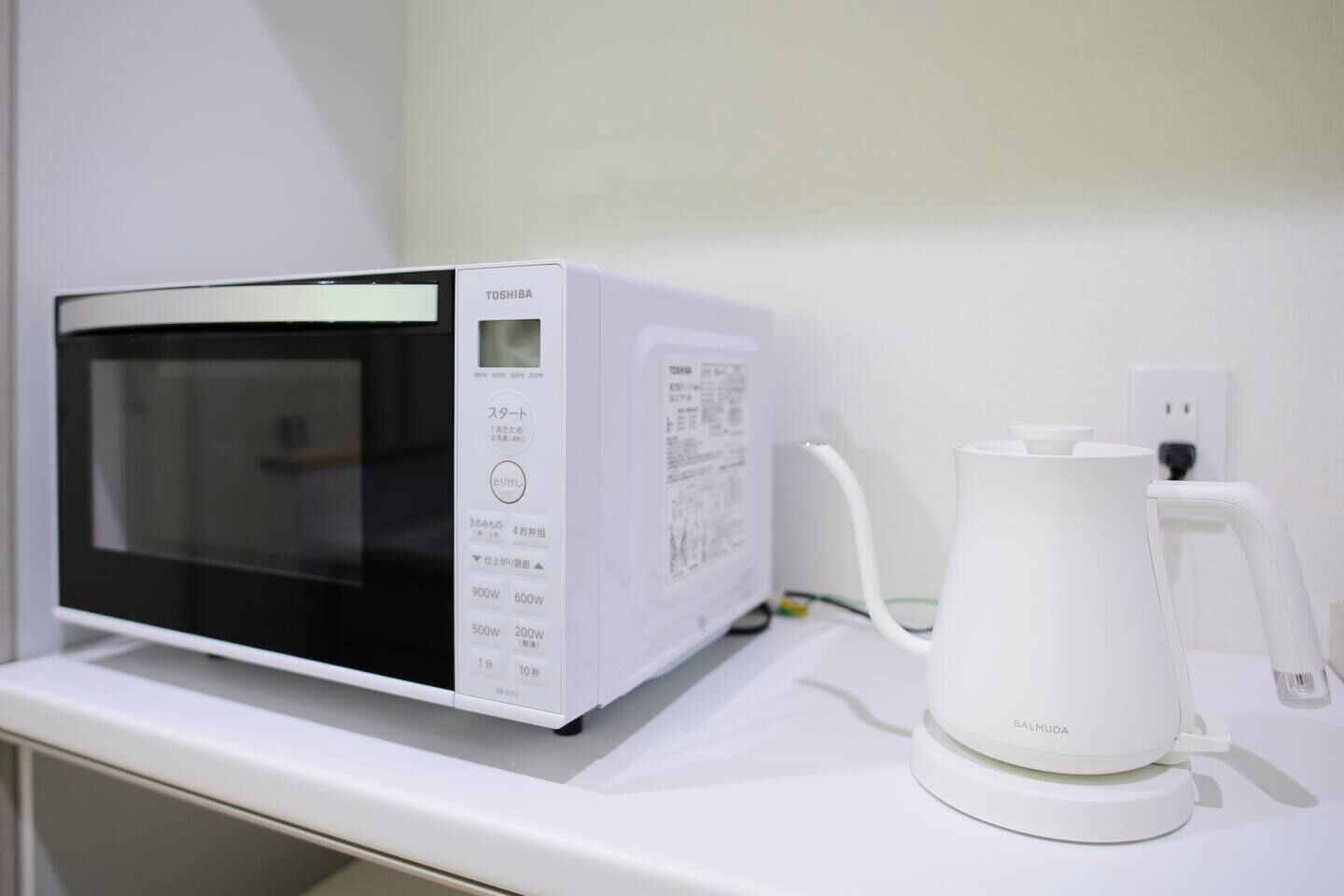 A microwave and a coffee maker on a white countertop.
