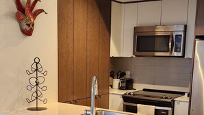 A modern kitchen with a central island, stainless steel appliances, and a decorative mask on the wall. - Luxury Condo Toronto YYZ (Toronto)