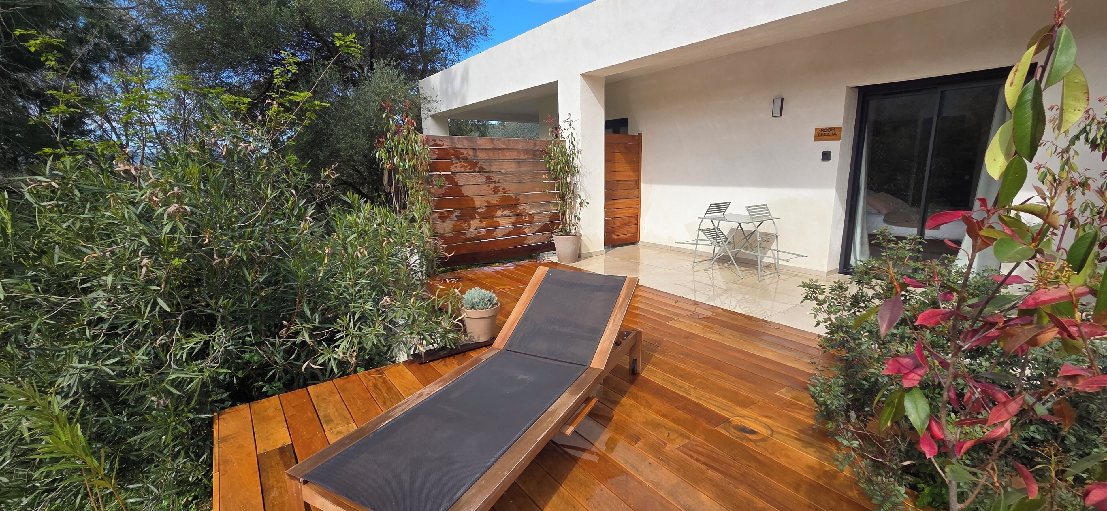 Un patio extérieur moderne avec une terrasse en bois, un fauteuil de relaxation et une petite table.