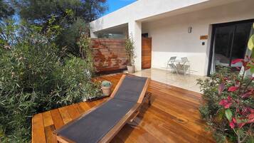 Un patio extérieur moderne avec une terrasse en bois, un fauteuil de relaxation et une petite table.
