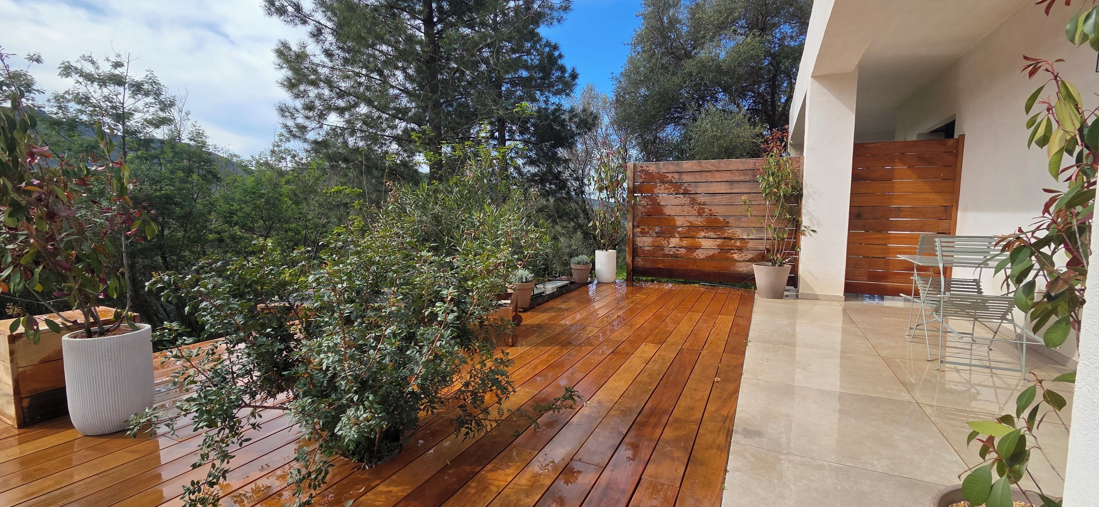 Una terraza de madera con macetas, una cerca de madera y una zona de estar.