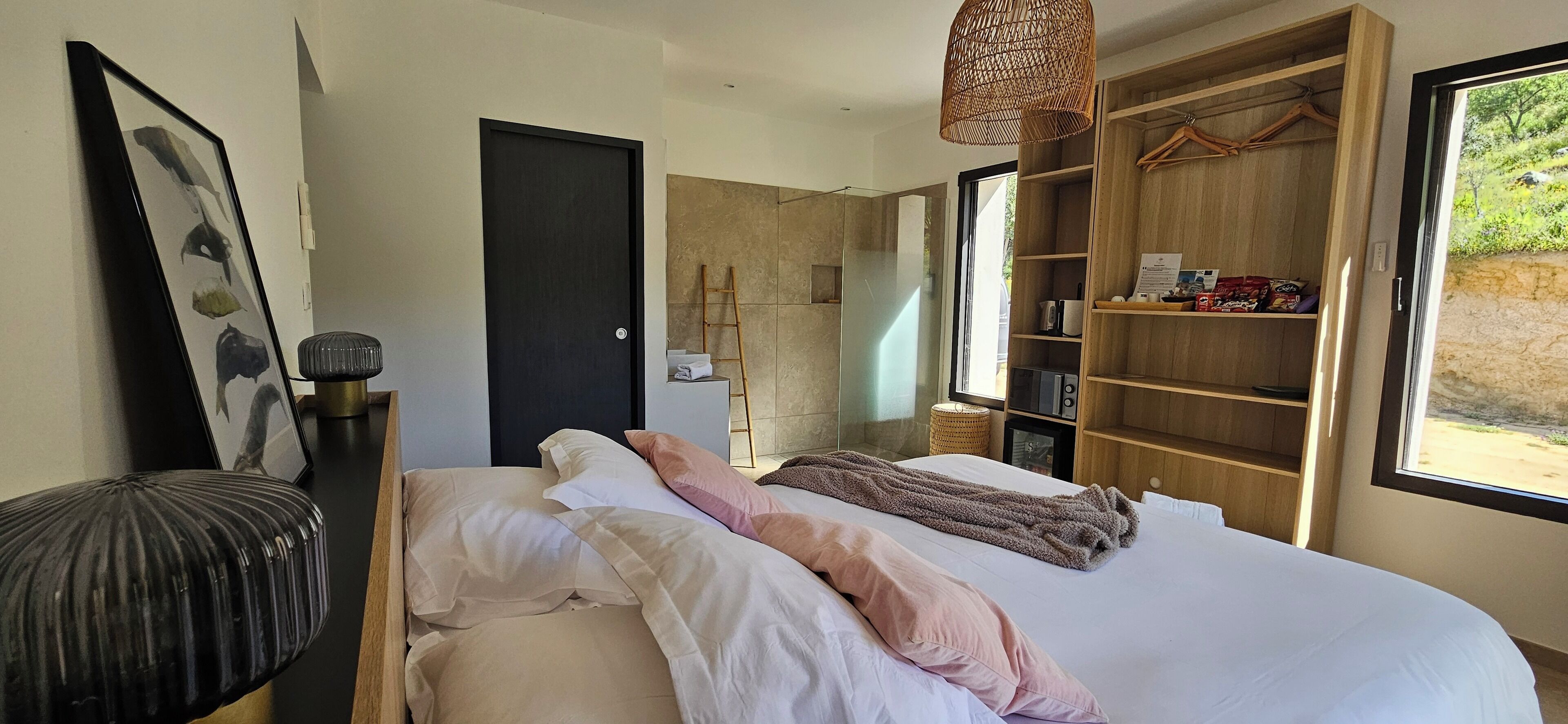 Una camera da letto moderna con un letto grande, un armadio, un comodino e una lampada a sospensione.