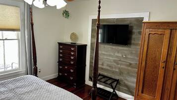 Une chambre à coucher comprenant un lit, une commode, une armoire et un téléviseur fixé au mur, qui est en bois.