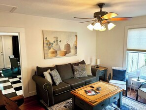 A living room with a sofa, coffee table, and a ceiling fan. - Morgan House | Historic Suite with Hot Tub Downtown (Ocala)