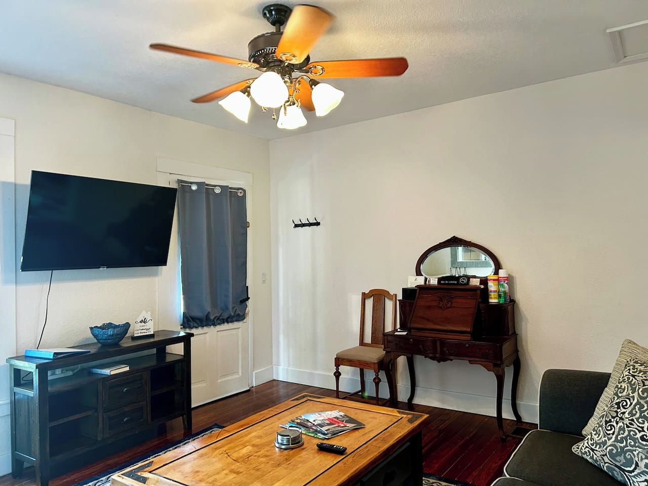 A living room with a television, a wooden coffee table, a piano, and a ceiling fan.