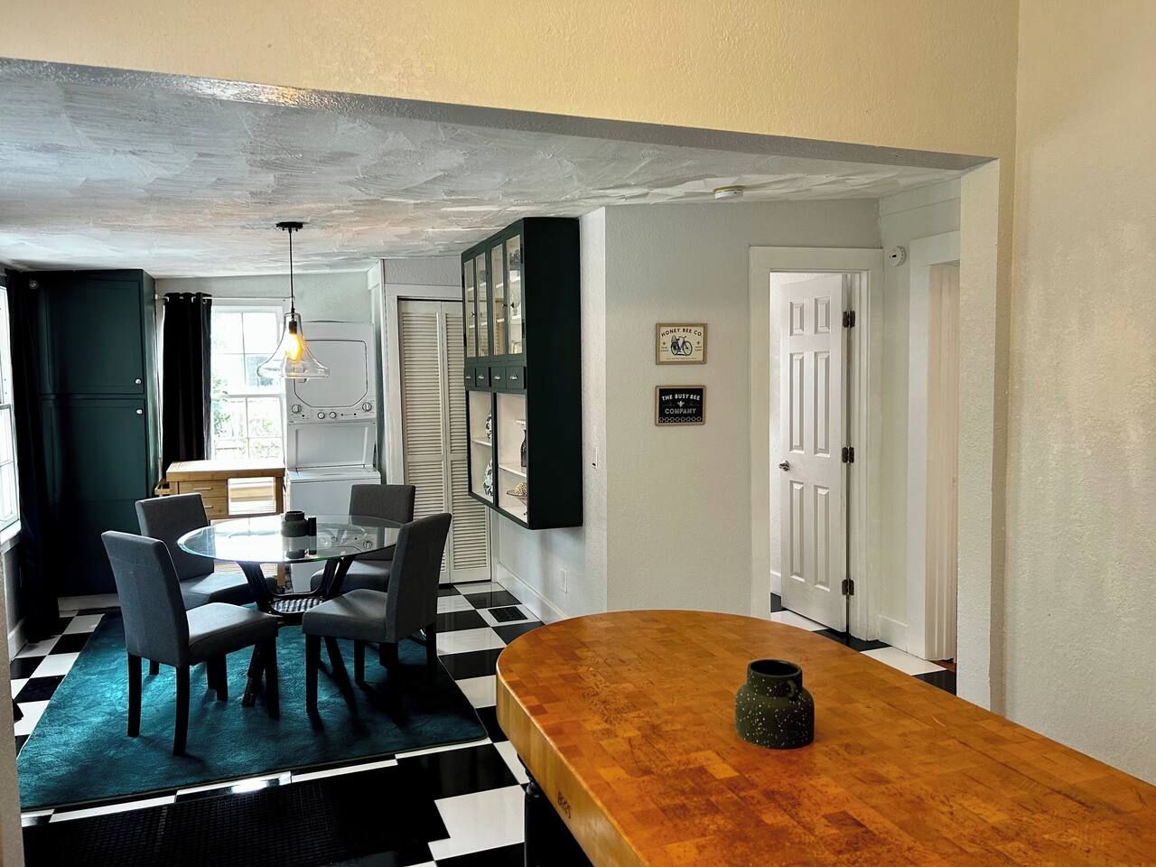 A dining area with a round table, chairs, and a checkered floor.