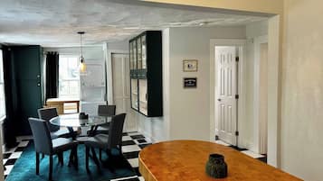 A dining area with a round table, chairs, and a checkered floor.