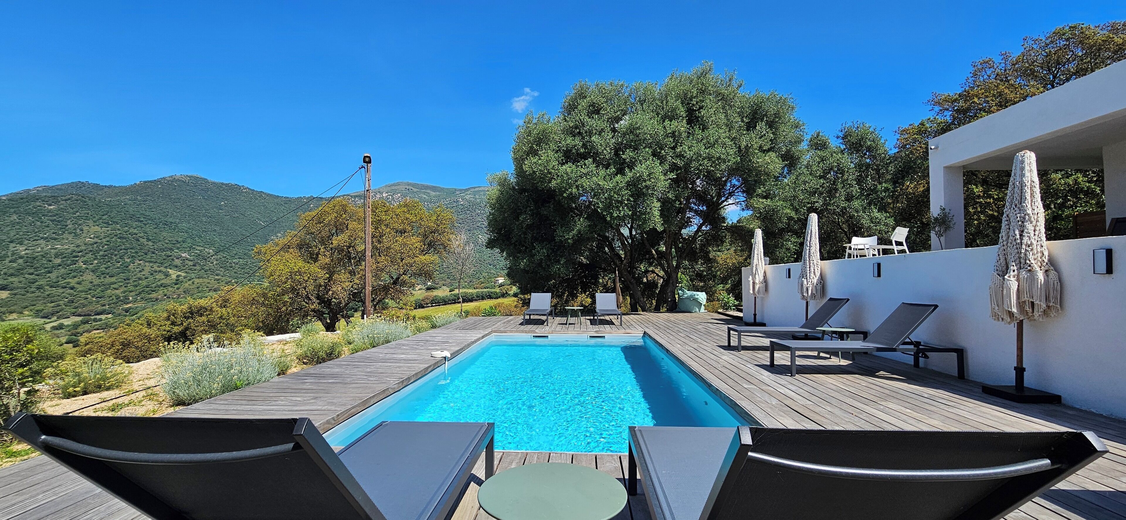 Ein Poolbereich mit Liegestühlen und Blick auf eine Berglandschaft.