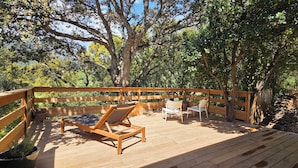 A wooden deck with lounge chairs and a wooden fence.