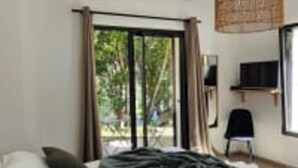 A bedroom with a bed, a television, and a window with curtains.