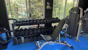 A gym with a bench press, dumbbells, and weight machines. - Charming Log Home on acreage bordering golf course with full gym (Port Alberni)