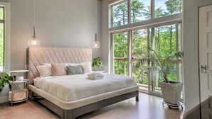 Una camera da letto con un letto grande, un ventilatore a soffitto e una finestra vista alberi.