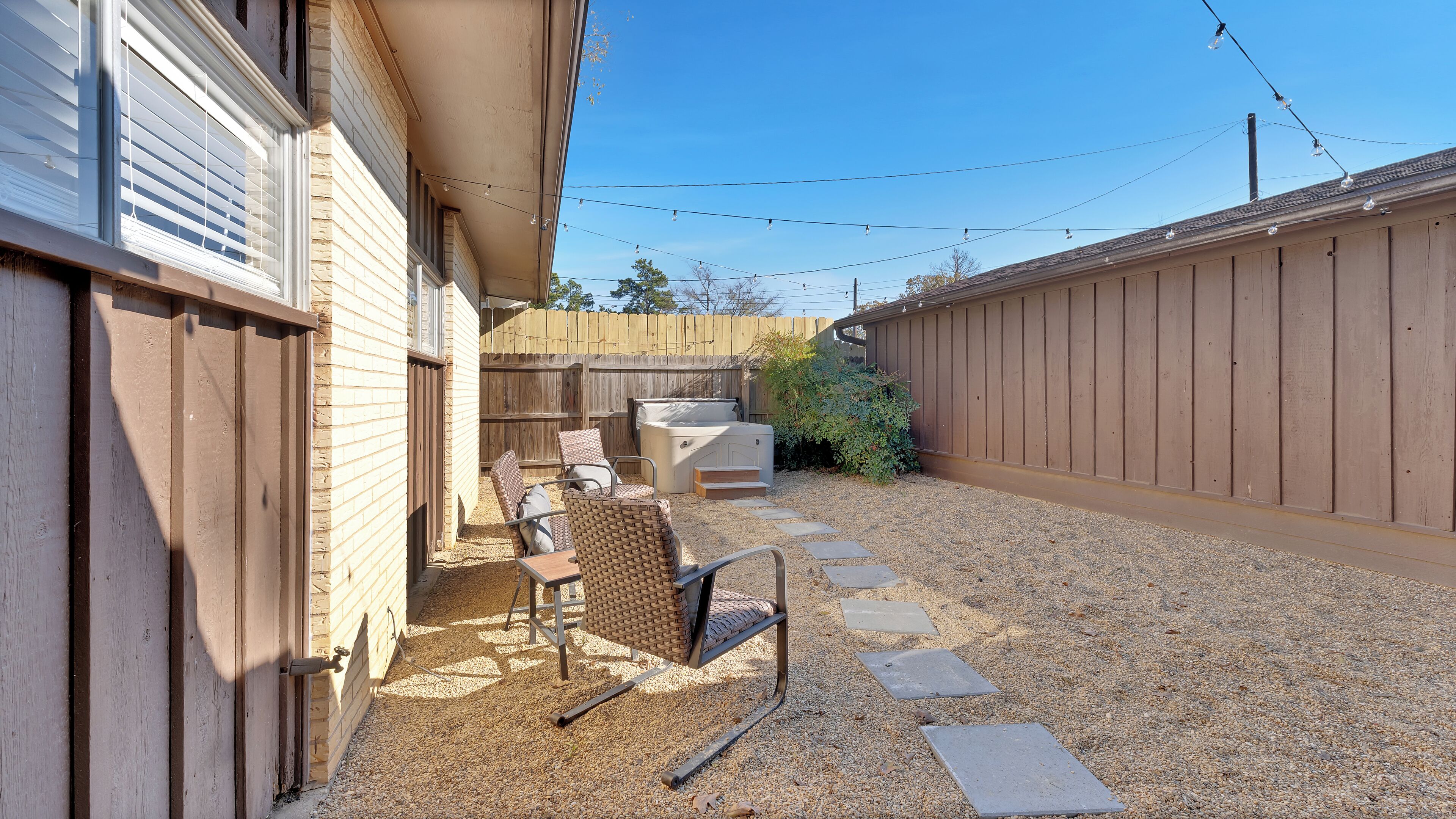 Un jardin avec un jacuzzi, des meubles de patio et une clôture en bois.