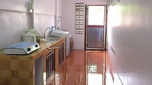 A kitchen with a tiled floor, a countertop with appliances, and a window with blinds. - Buriram The Big House Intown (Buriram)