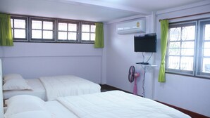A hotel room with two beds, a TV, an air conditioner, and a window with curtains. - Buriram The Big House Intown (Buriram)