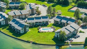 A residential complex with multiple buildings, a swimming pool, and a waterfront.