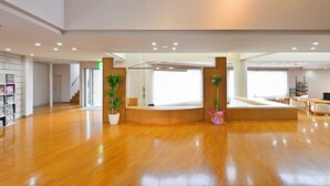 A spacious lobby with a wooden floor, a reception desk, potted plants, and a staircase leading to upper floors. - LiVEMAX Resort Yatsugatake Kogen (Hokuto)