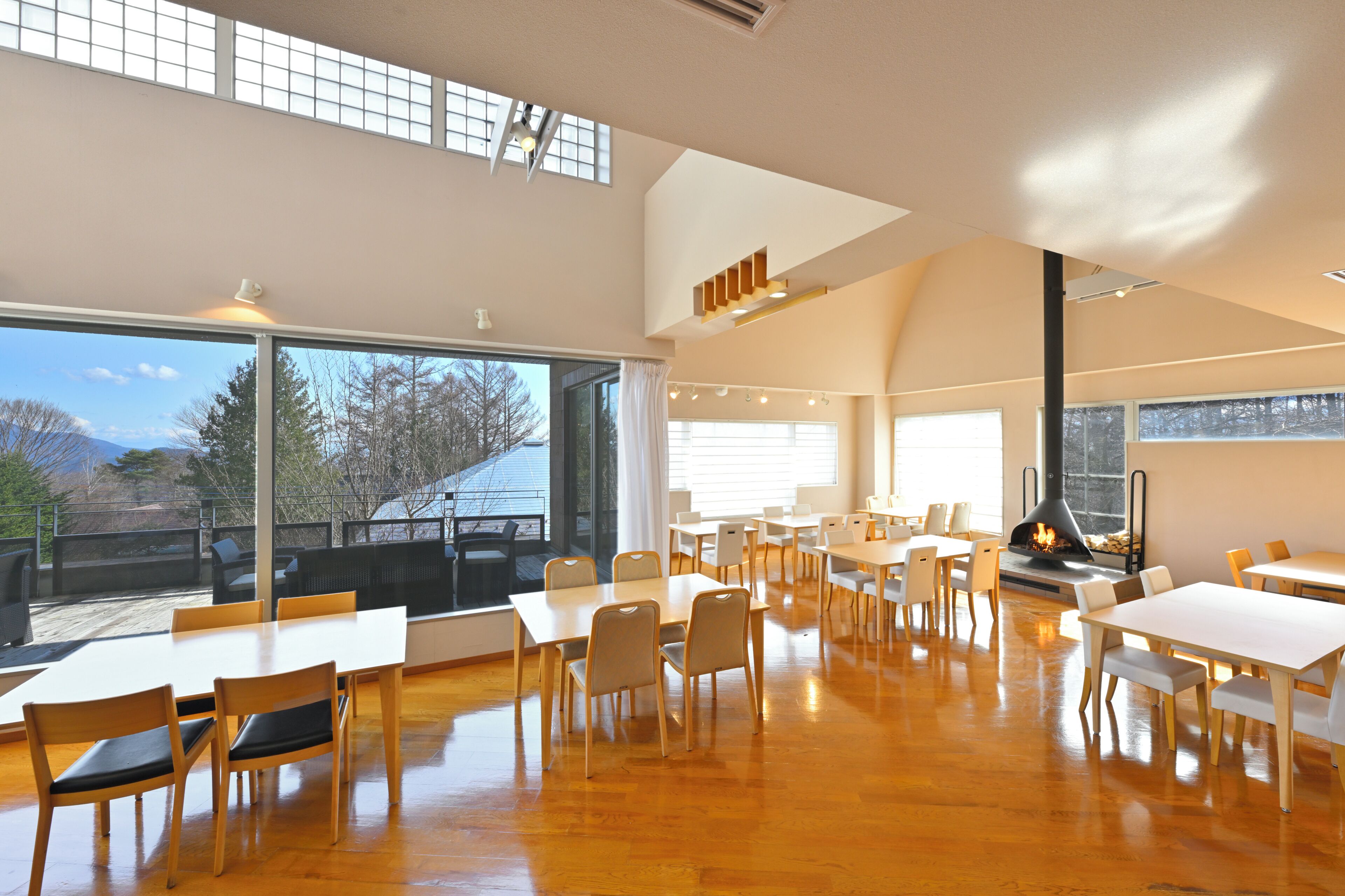 A spacious dining area with high ceilings, large windows, and a fireplace.
