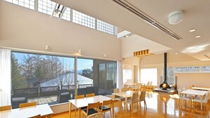A spacious dining area with large windows, a fireplace, and a high ceiling. - LiVEMAX Resort Yatsugatake Kogen (Hokuto)