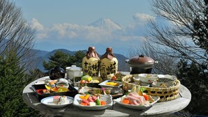 A table with various dishes and a view of a mountain. - LiVEMAX Resort Yatsugatake Kogen (Hokuto)