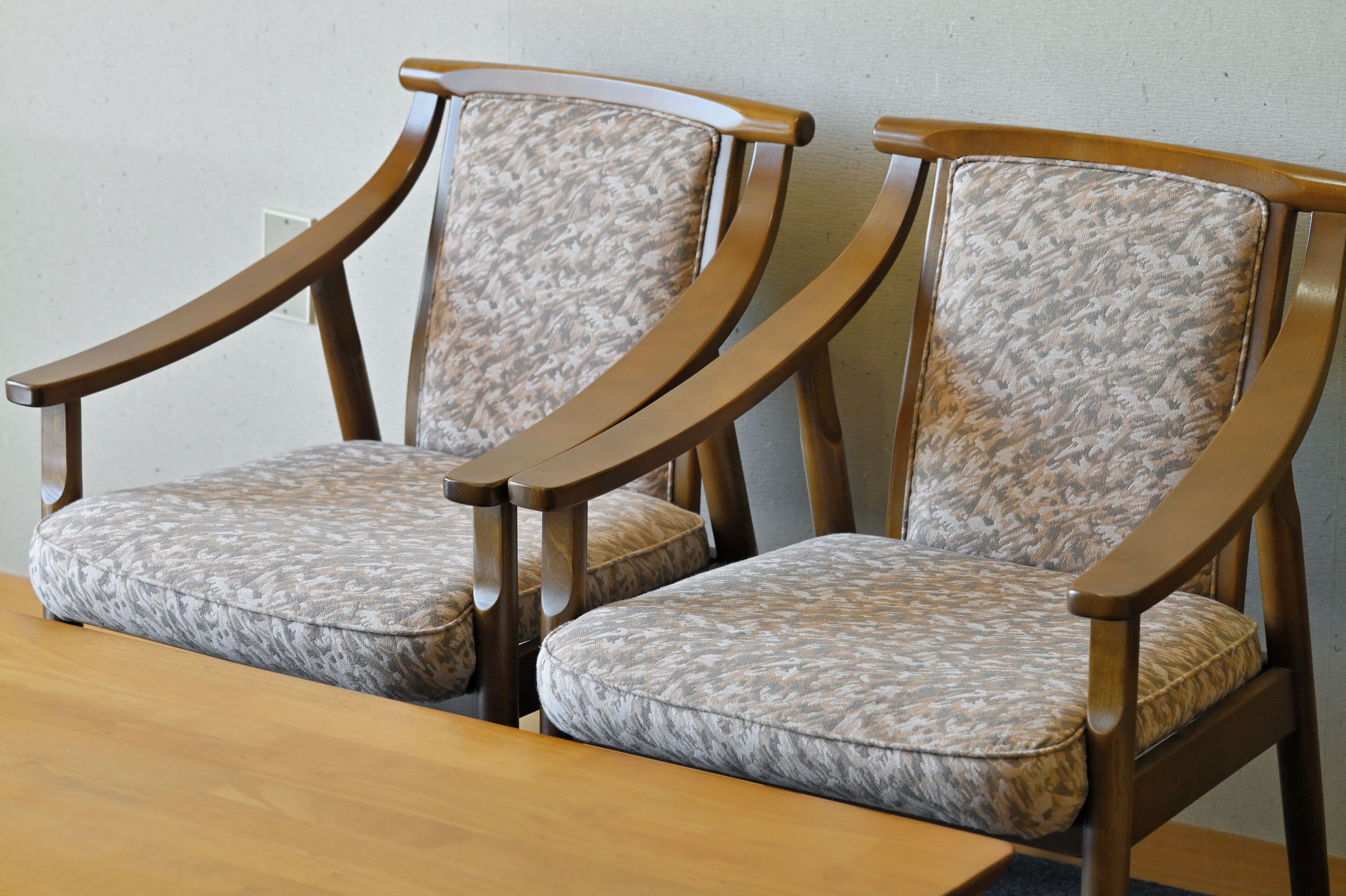 Deux chaises en bois avec des coussins à motifs et une table en bois.