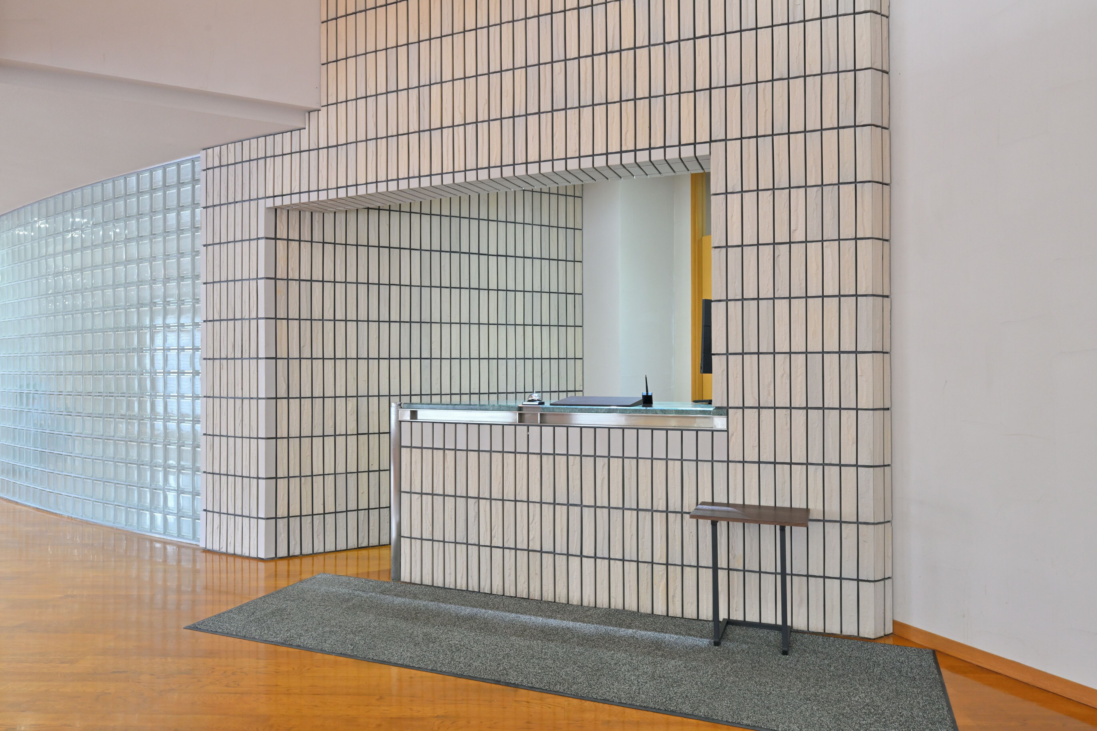 A modern bathroom with a tiled wall, a sink, and a mirror.