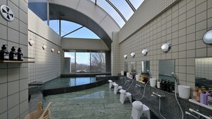 A modern bathroom with a large skylight, a central pool, and multiple sinks. - LiVEMAX Resort Yatsugatake Kogen (Hokuto)