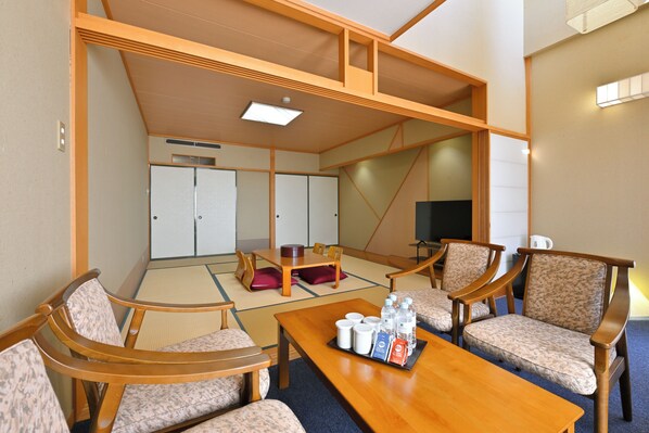 A traditional Japanese room with tatami flooring, wooden furniture, a television, and a tray with bottled water and tea. - LiVEMAX Resort Yatsugatake Kogen (Hokuto)