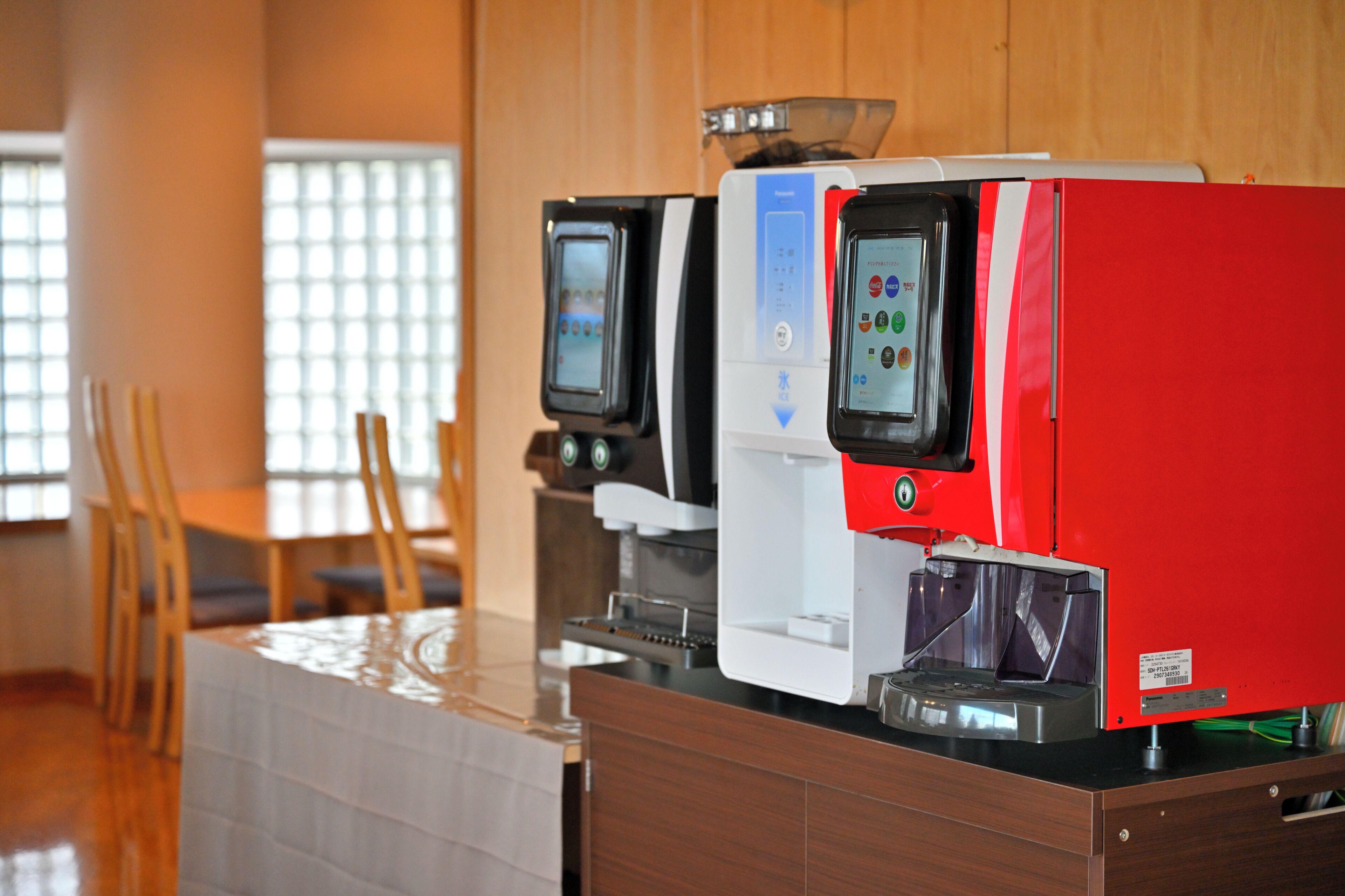 Una máquina de café y un dispensador de té en una habitación con paredes de madera y suelo de baldosas.