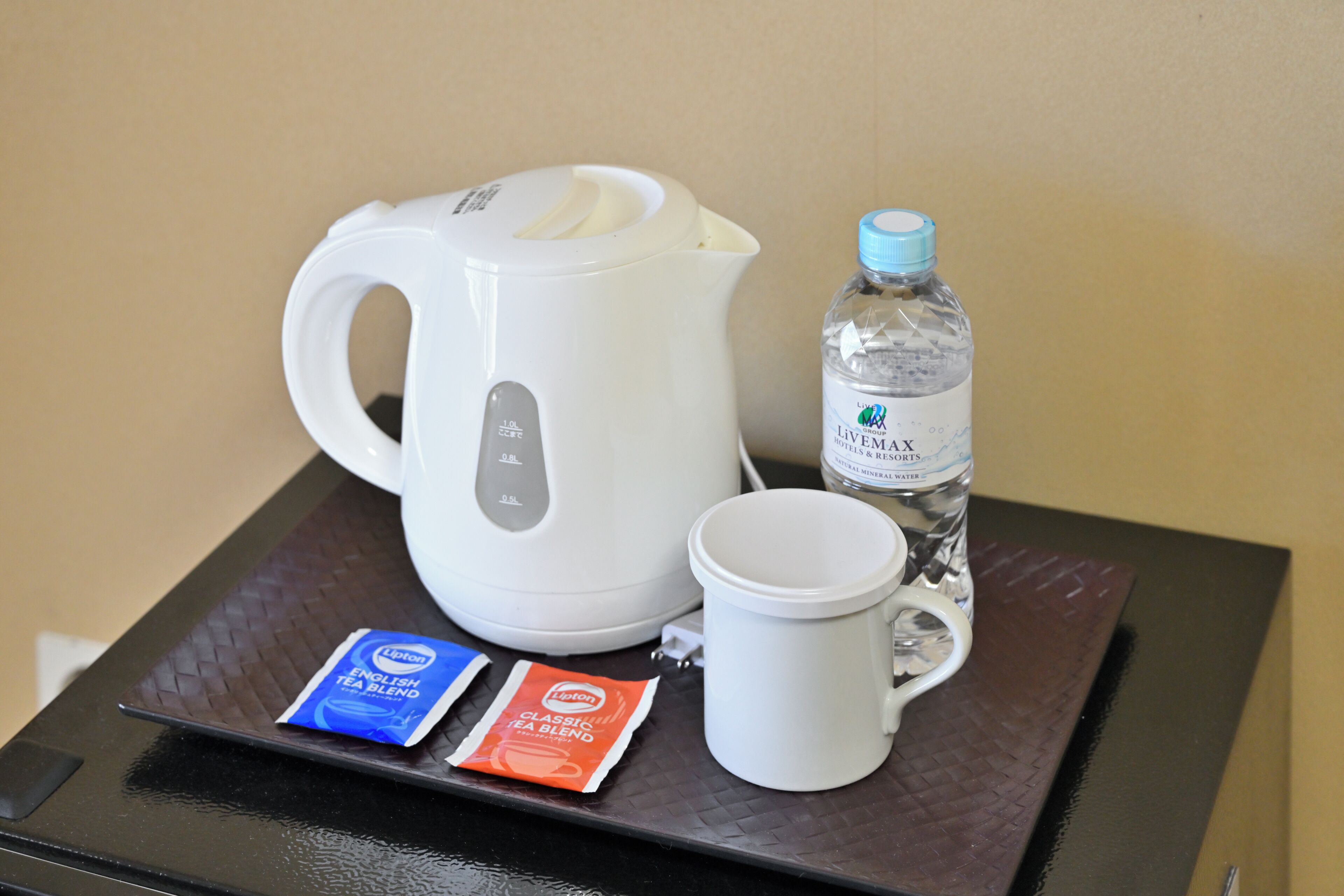 A kettle, a water bottle, and tea packets on a tray.
