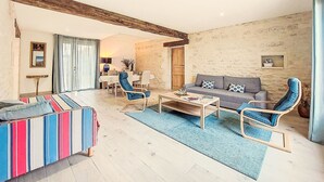 A living room with a sofa, armchairs, a coffee table, and a striped ottoman. There is a dining area with a table and chairs in the background. - Ile d'Aix by Interhome (Geay)