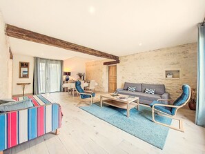 A living room with a sofa, armchairs, a coffee table, and a striped ottoman. There is a dining area with a table and chairs in the background. - Ile d'Aix by Interhome (Geay)