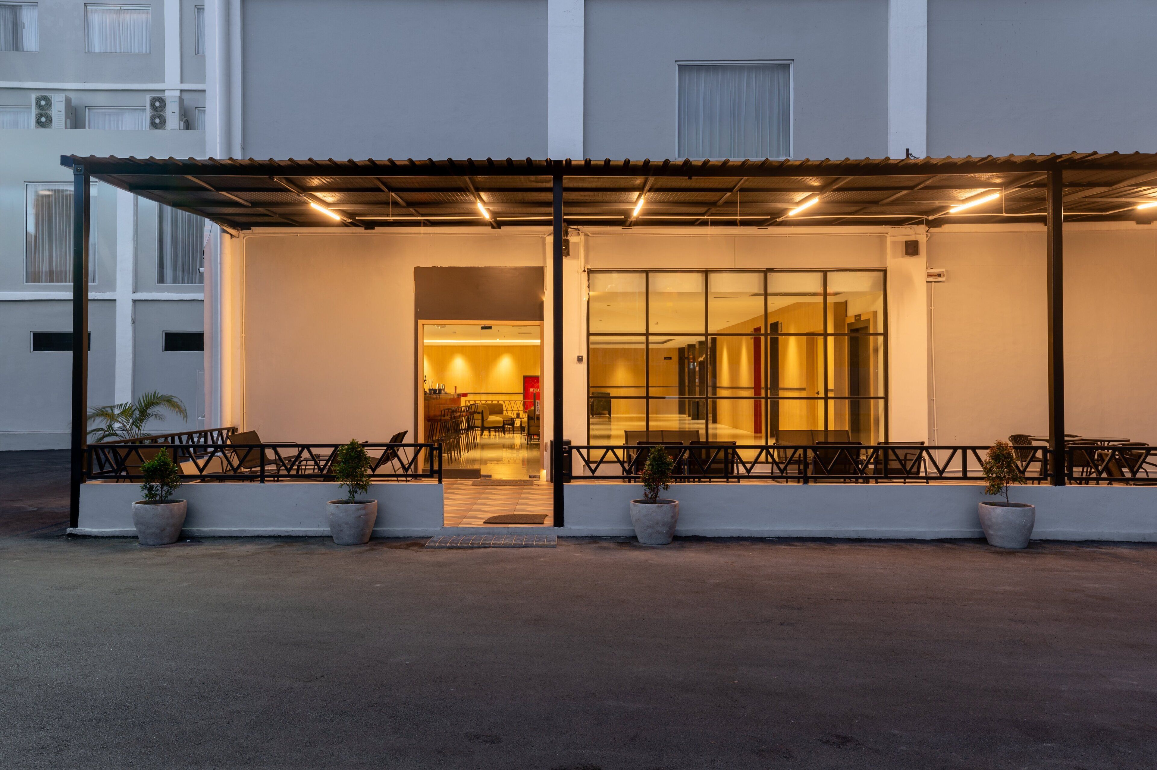 A hotel entrance with a covered outdoor seating area, potted plants, and a glass door leading inside.