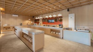 A modern kitchen with wooden cabinetry, a central island, and pendant lighting. - MAXONE Batam (Batam)