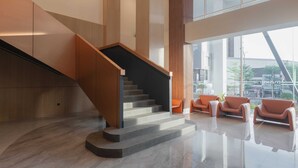 A modern interior with a staircase, seating area, and large windows. - MAXONE Batam (Batam)