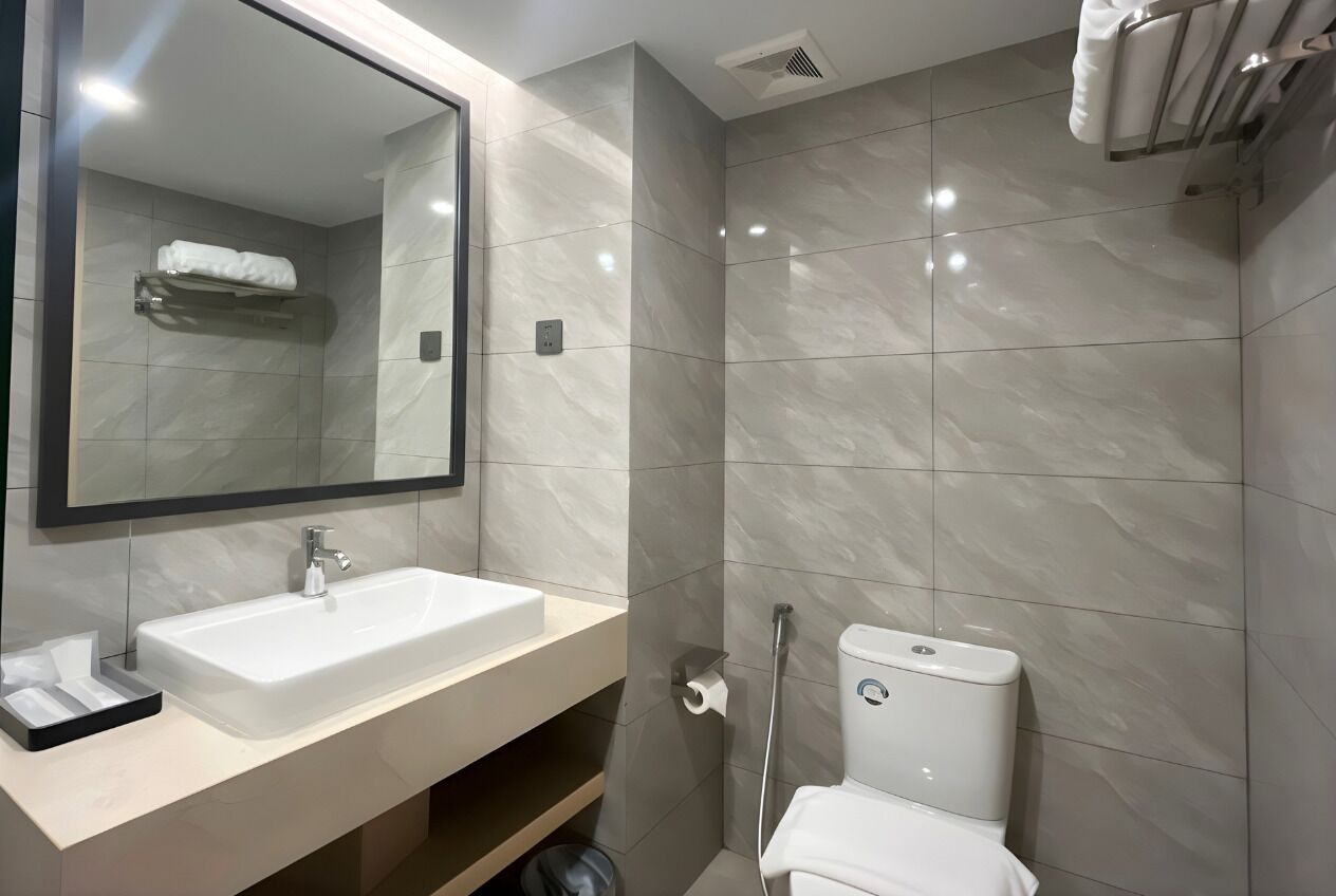A modern bathroom with a large mirror, a sink, a toilet, and a towel rack.