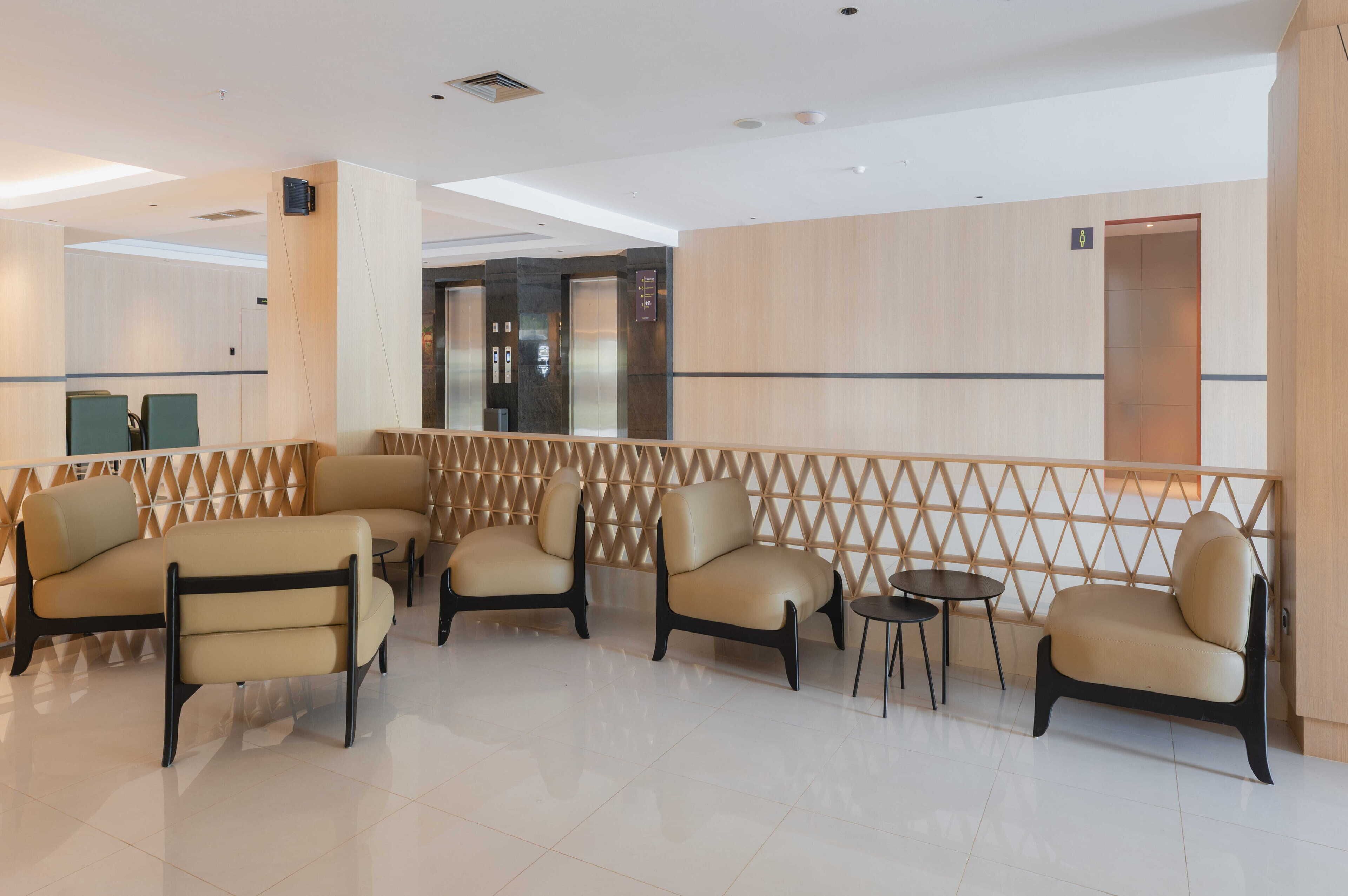 A modern lobby with seating areas, a reception desk, and an elevator.