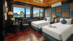 Una habitación con dos camas, una mesita con una silla y vista al mar.