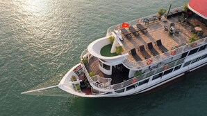 Un barco de crucero fluvial con una cubierta que cuenta con sillones, mesas y plantas en macetas.