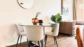 A modern living room with a round mirror, a round table with two chairs, a sofa, and a large plant. - Luxe Marina Escape-Near SoFi & Beaches (Marina del Rey)