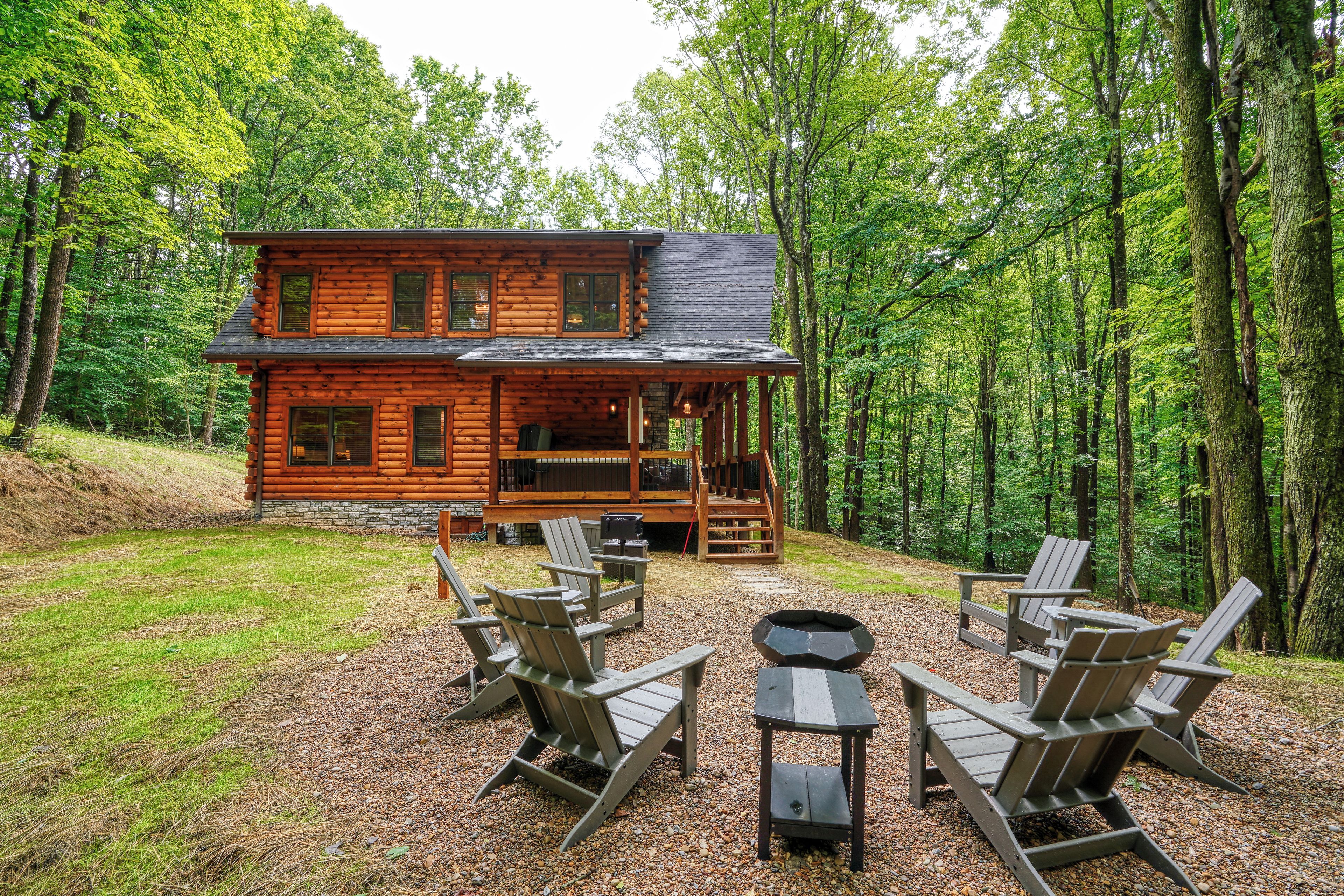 A log cabin with a porch, outdoor seating, and a fire pit.