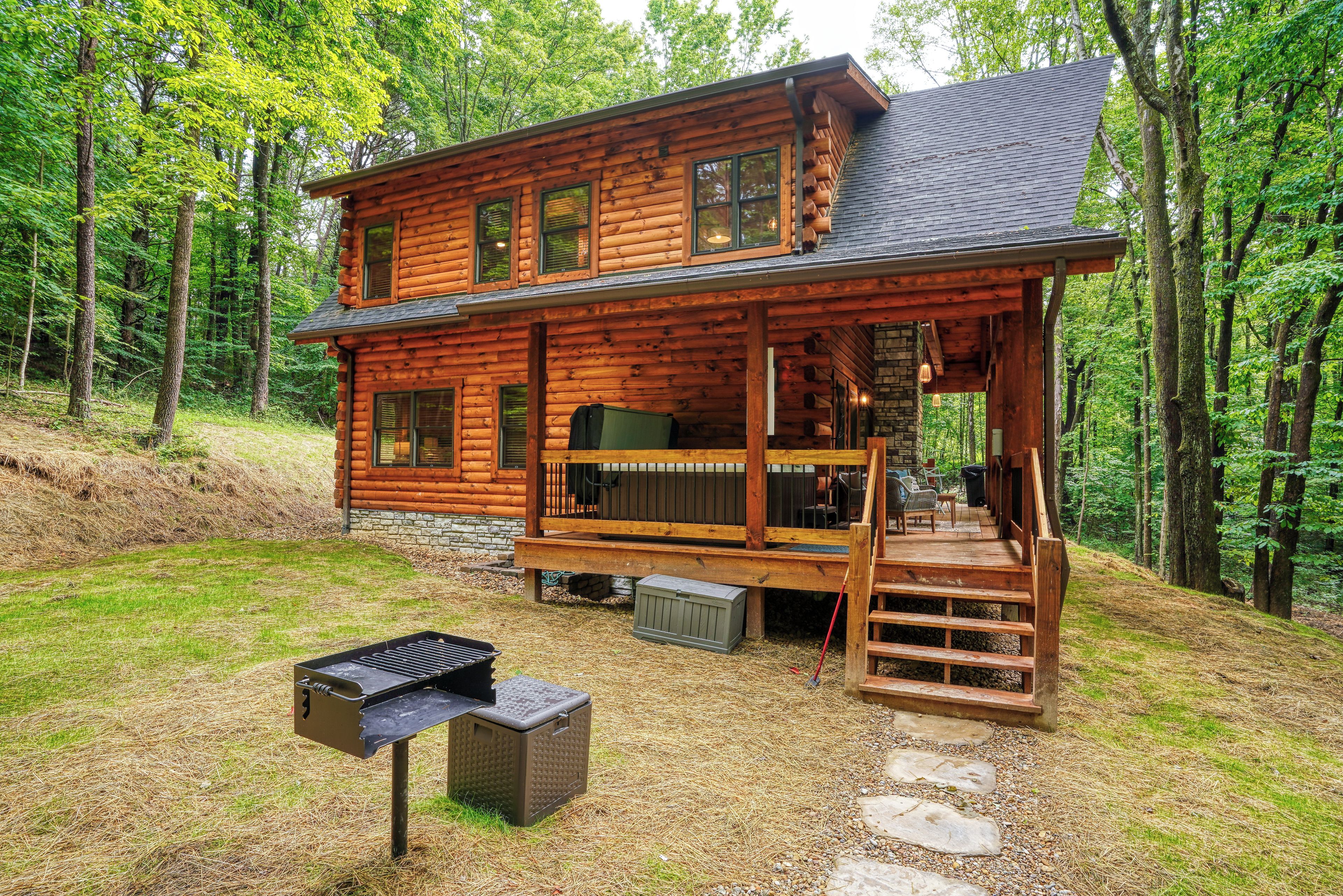 A wooden cabin with a deck, a grill, and a stone pathway.
